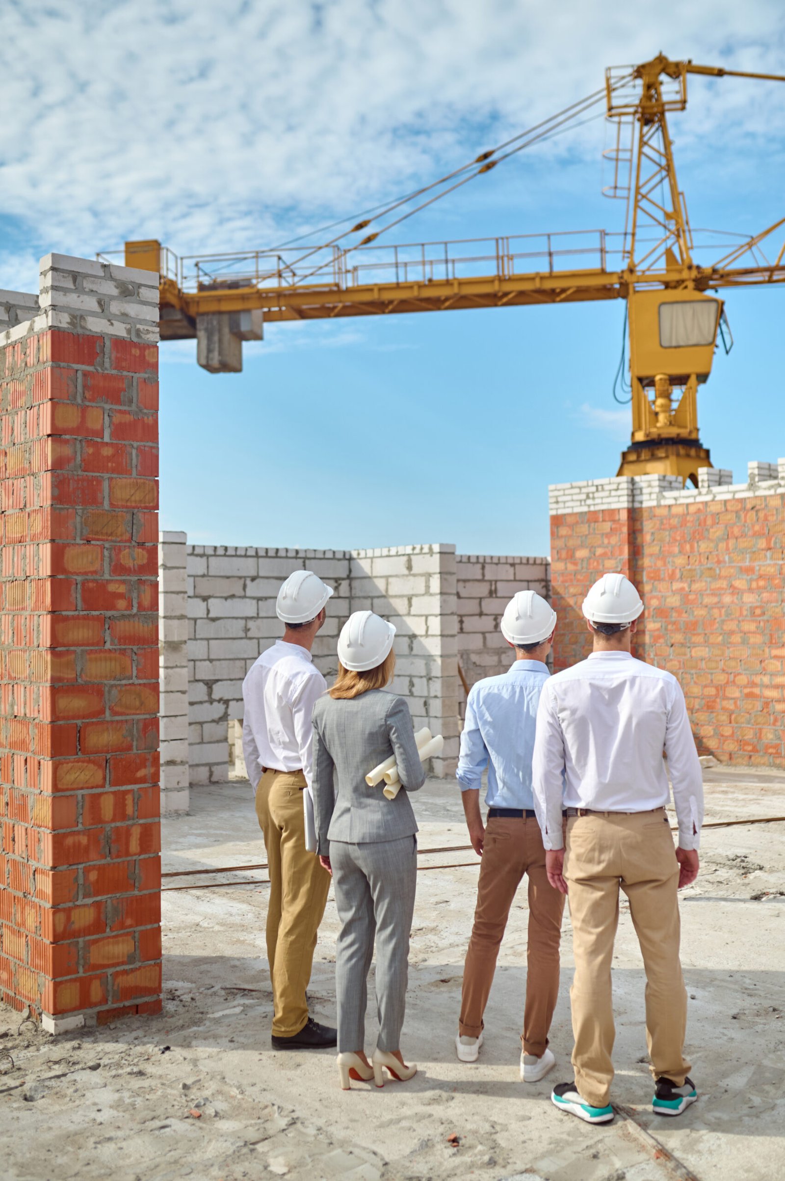 four people protective helmets inspecting building area scaled